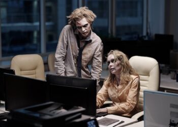 Premium Photo | Young spooky zombie businessman standing next to female  colleague sitting by desk in front of computer monitor during teamwork